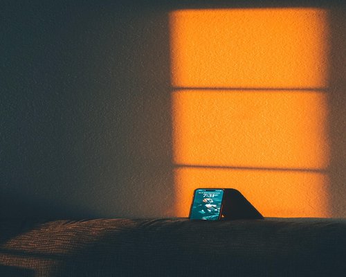 A smartphone screen dimmed down properly matching a cozy ambient warm light background room