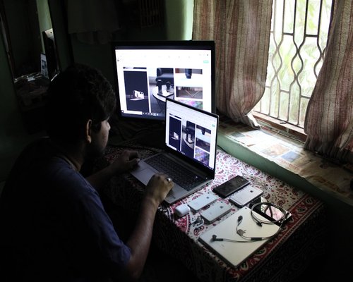 A person managing computer screen brightness next to a window with diffused morning light